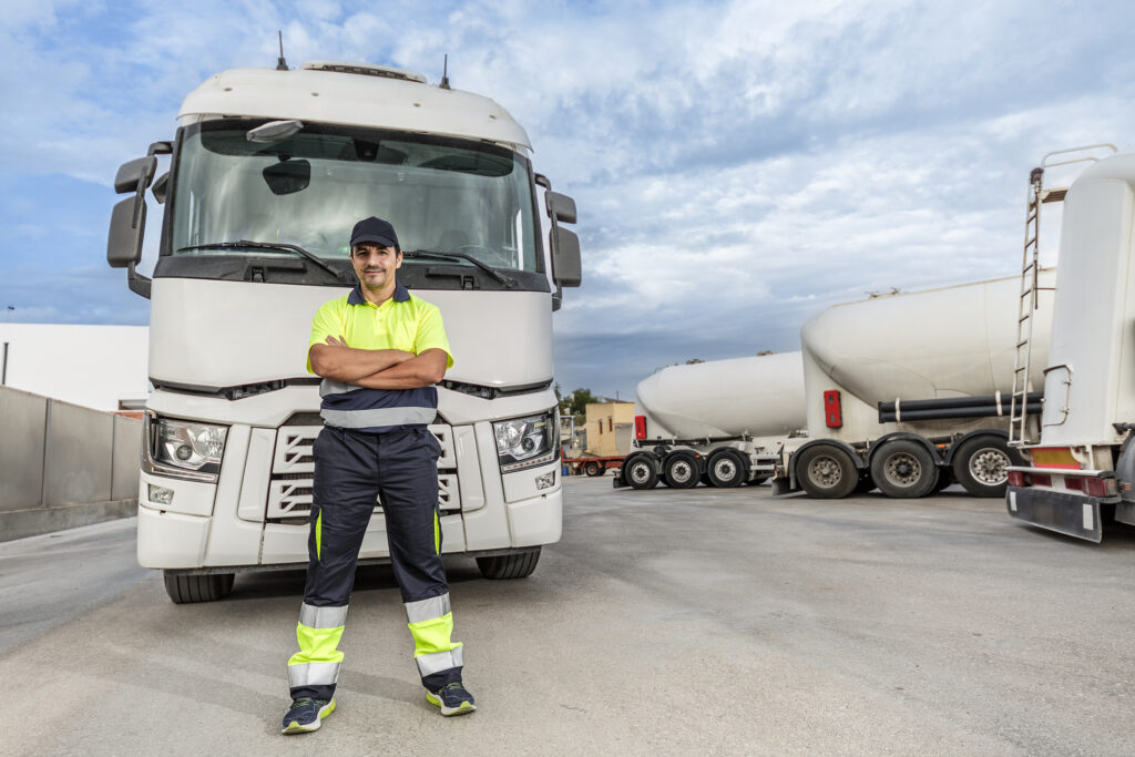 Smiling adult man mechanic standing in front of parked truck